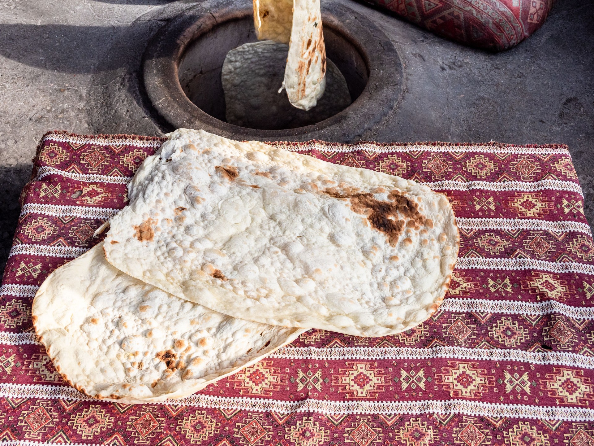 taking out baked lavash from wall of tandoor